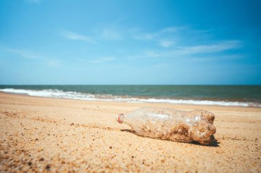 Plastik şişe kum plajı arka planında. Doğa ve çevre kavramı.