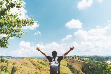 Mavi gökyüzü ve beyaz bulut soyut arkaplan üzerinde insan dağın tepesinde el kaldırır. Özgürlük iyi hissettiriyor ve seyahat macerası konsepti. Klasik ton filtre efekti renk biçimi.