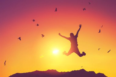 Siluet adam zıplıyor ve kuşlar gün batımında gökyüzünde uçuyor ve soyut arkaplan dokusunu bulutlandırıyor. İyi hissetme özgürlüğü ve seyahat macerası konseptini kopyala. Klasik ton filtre efekti renk biçimi.
