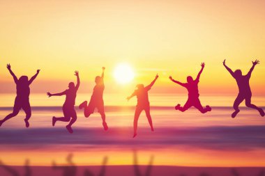 Mutlu arkadaş tropik günbatımı sahili arka planında atlıyor. Arkadaşlık özgürlüğü tatili ve seyahat tatili takım çalışması konseptini kopyala. Klasik ton filtre efekti renk biçimi.