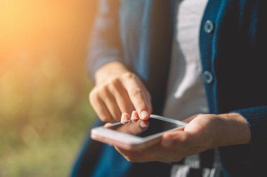 Açık hava parkının arka planında akıllı telefon kullanarak kadının elini tut. Teknoloji ve seyahat tatil konseptinin kopyalama alanı. Klasik ton filtre efekti renk biçimi.