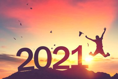 Silüet adam atlıyor ve kuşlar gün batımında dağın tepesinde gökyüzünde uçuyor ve sayı 2021 gibi soyut bir arka plan. Mutlu yıllar ve bayram kutlamaları. Klasik ton filtresi renk biçimi.