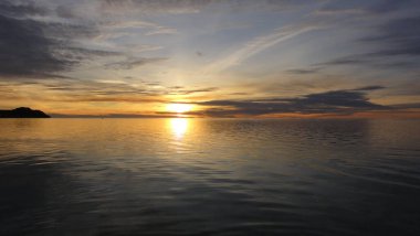 Tropikal bir adada denizin üzerinde güneşli bir gün batımı