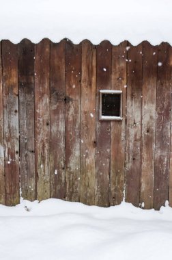 Küçük pencereli, karla kaplı eski ahşap kulübenin ayrıntıları..