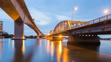 Alacakaranlık gökyüzü ile nehir üzerinde çapraz köprü 