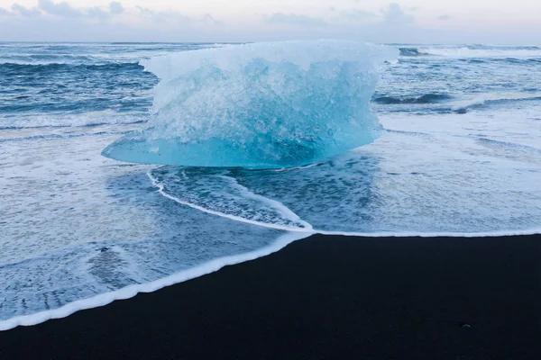 冬に黒い砂のビーチに壊れる氷 — ストック写真