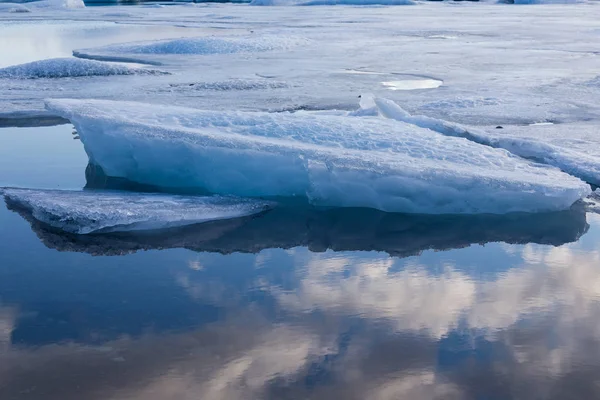 Iceberg breaking over ice floor with blue sky reflection — Stock Photo, Image