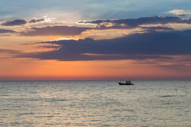 Sahil manzarası ile günbatımı arka plan üzerinde küçük balıkçı teknesi