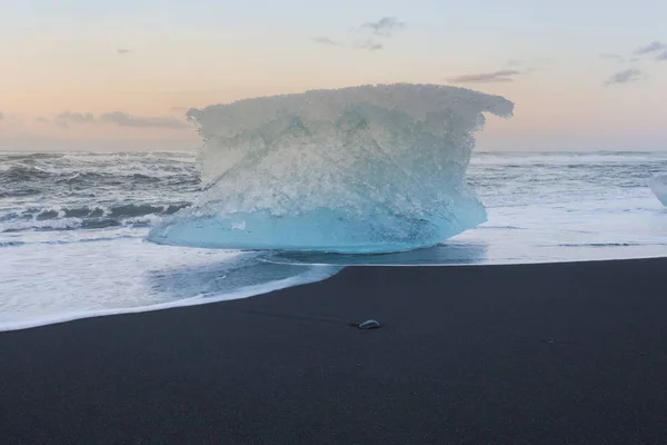 Ice breaking from iceberg on black sand beach, Iceland winter season