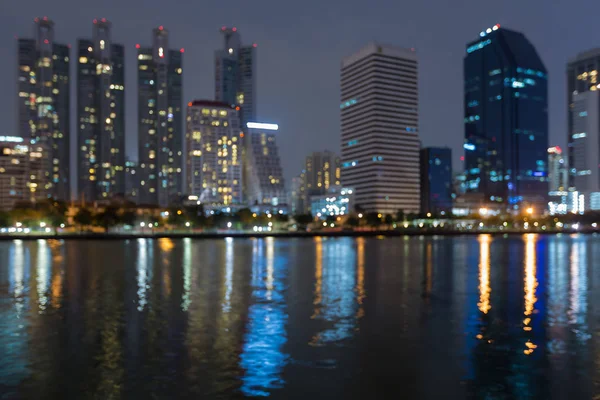 Night blurred bokeh light office building with water reflection, — Stock Photo, Image