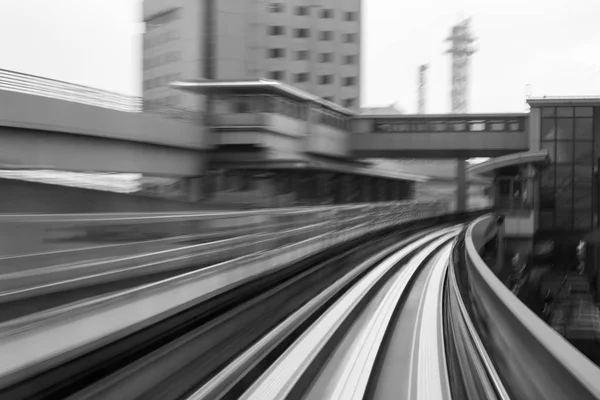 Černou a bílou, rozostření pohybem železniční trati zakřivené vedoucí k nádraží — Stock fotografie