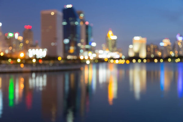 Twilight blurred bokeh city office building with water reflection, abstract background