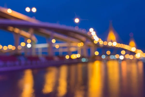 Noite crepúsculo embaçado bokeh luz ponte e estrada rio frente — Fotografia de Stock