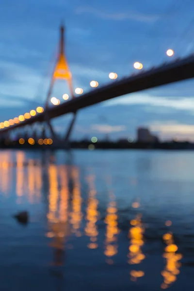 Night blurred bokeh suspension bridge with reflection at twilight — Stock Photo, Image