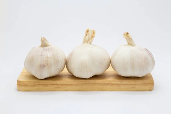 Three garlic on wooden board, on white — Stock Photo, Image