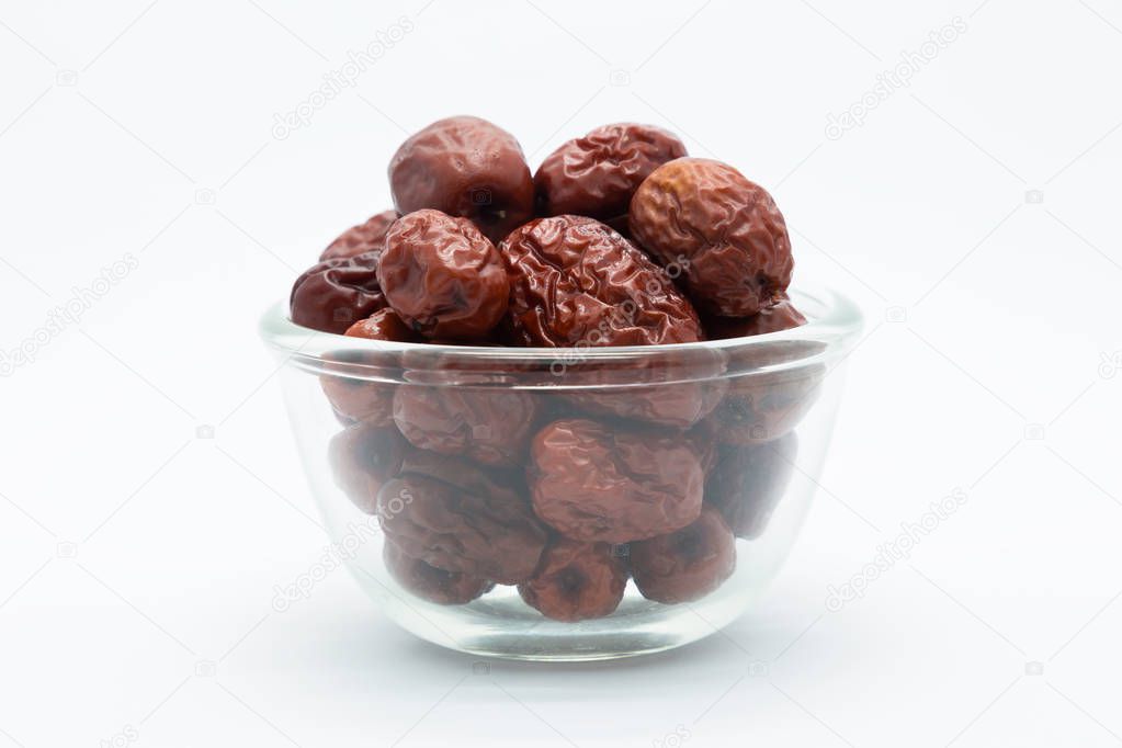Glass cup of dried red jujube on white 
