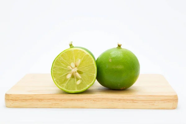 Limes vertes coupées fraîches sur panneau en bois — Photo