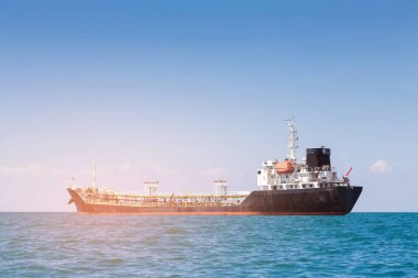 Oil Ship tanker over sea coast skyline, with clear blue sky background  clipart