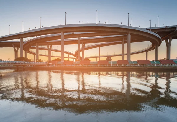 Sunset over highway interchange reflection over river, transportation background