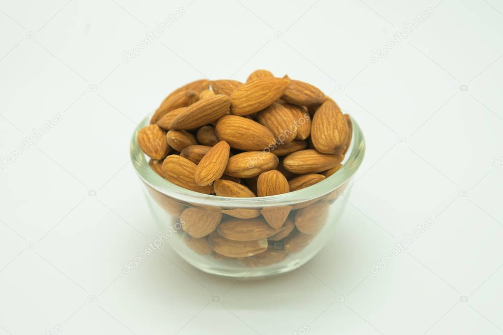 Brown almond on glass cup, on white background