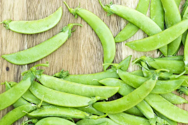 Bezelyeler, olgun yeşil bezelyeler ahşap masada.