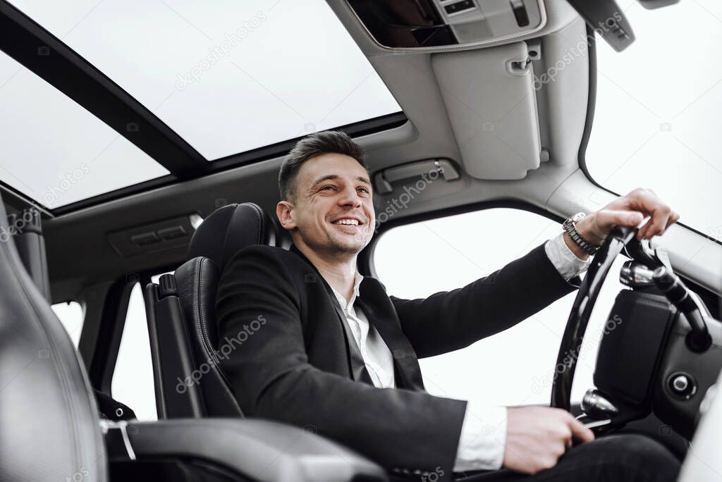 Happy young businessman having test drive new car. Rent and trade-in concept