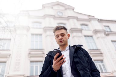 Genç adam cep telefonunu dışarıda tutuyor.
