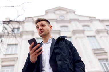 Sokakta telefonunu tutan yakışıklı adam.