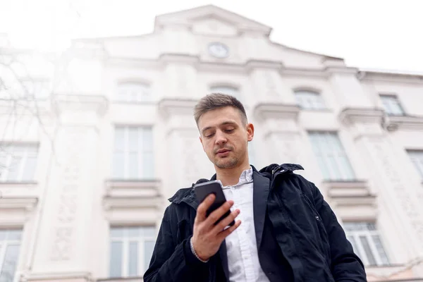 Genç adam cep telefonunu dışarıda tutuyor.