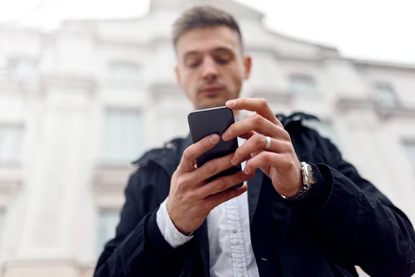 Hombre joven mirando la pantalla del teléfono inteligente al aire libre — Foto de Stock