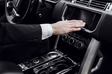 Erkek el otomobilde radyoyu değiştiriyor.