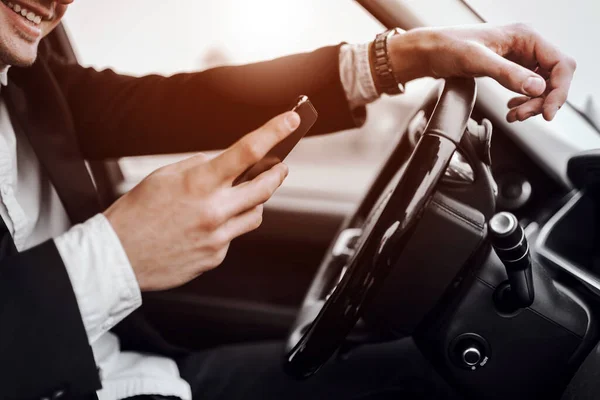 Un jeune homme souriant tient son téléphone portable dans sa voiture — Photo