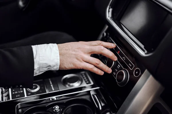 İş adamı otomobil sürerken radyo istasyonu değiştiriyor