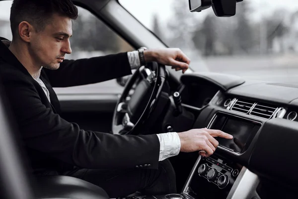 Businessman in jacket sitting in modern automobile