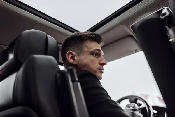 Serious handsome man driving automobile in the city — Stock Photo, Image