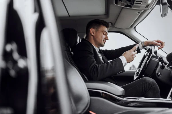 Happy businessman looking at phone screen in car