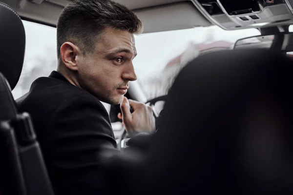 Kendine güvenen işadamı modern otomobilde oturuyor.