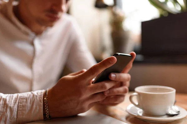 Manos masculinas sosteniendo el teléfono móvil en la cafetería — Foto de Stock