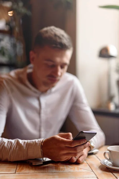 Kahve dükkanında cep telefonuyla yazan bir işadamı.