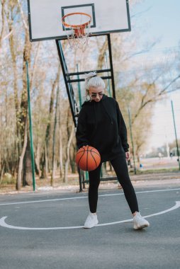 Sahada basketbol oynayan gözlüklü güzel bir kadın.