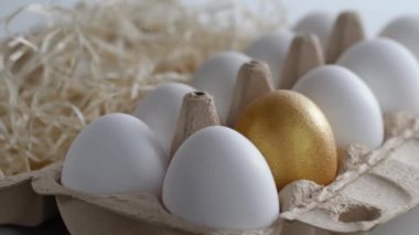 Sabah ışığında saman ve taze ve seçilmiş tavuk yumurtalarıyla dolu bir yumurta tepsisinin yakın çekimi. Beyaz ve altın rengi. Çember dönüşü. Yan görüş. Portre oryantasyonu. Ürününüz için sağlıklı beslenme veya illüstrasyon kavramını temsil edin 