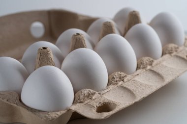 Saman ve taze ve seçilmiş beyaz tavuk yumurtalarıyla dolu bir yumurta tepsisinin yakın çekimi. Yan görüş. Portre oryantasyonu. Ürününüz için sağlıklı beslenme veya illüstrasyon kavramını temsil edin