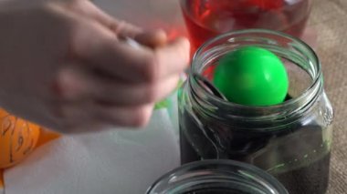 Bir kadın sanatçı kavanozdan paskalya yumurtalarını alır ve arka planda geleneksel arı cilası boyama tekniğiyle boyalı cam kaplar kullanır. Enfes ve sembolik Ukrayna halk tasarım güdülerini kullanarak. 