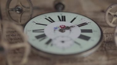 Saatin yüzünü, saatin ellerini gösteren antika bir saatin makro görüntüsü, ikinci el hareket halinde; çark arka planında, kamera yeniden odaklanıyor.