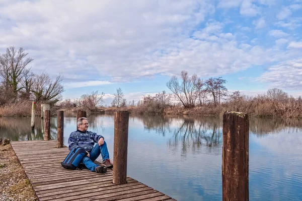 Senderista con mochila sobre muelle de madera en la orilla del río . — Foto de Stock