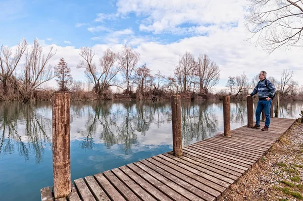 Senderista con mochila sobre muelle de madera en la orilla del río . — Foto de Stock