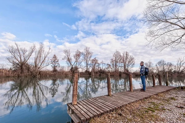 Senderista con mochila sobre muelle de madera en la orilla del río . — Foto de Stock