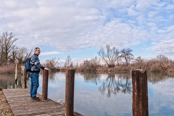 Senderista con mochila sobre muelle de madera en la orilla del río . — Foto de Stock