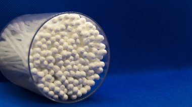 Plastik kavanozdaki pamuk tomurcukları mavi arka planda yatıyor..