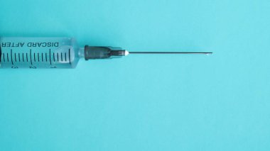 Aşıyla birlikte şırınga. Şırınganın ucuna bırak. Mavi arka plan. Sağlık ve tıp konsepti. Kas içi enjeksiyon. Aşı ampulde.